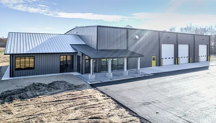 Large grey commercial pole barn featuring a dedicated glass front office space and a three-bay warehouse facility.