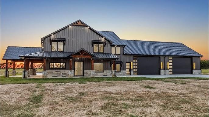 Modern dark grey custom barndominium featuring an attached two-car garage, large windows, and a covered front porch.