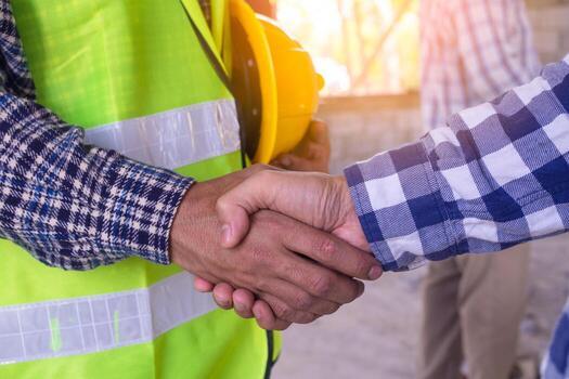 Up close shot of a construction worker shaking hands with a farmer.