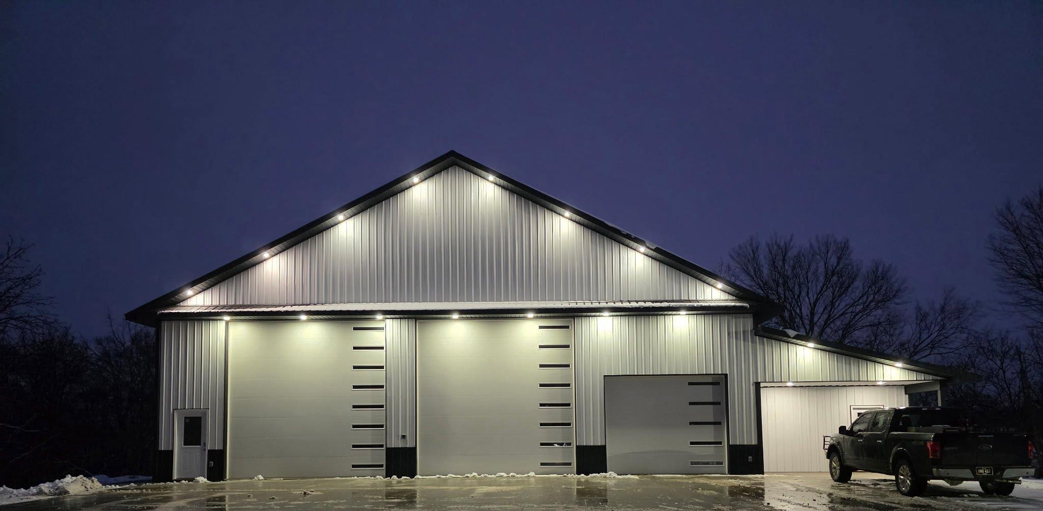 White shop building with large bay doors and a black roof.